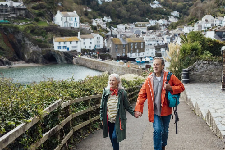 Two seniors walking alongside a lake holding hands