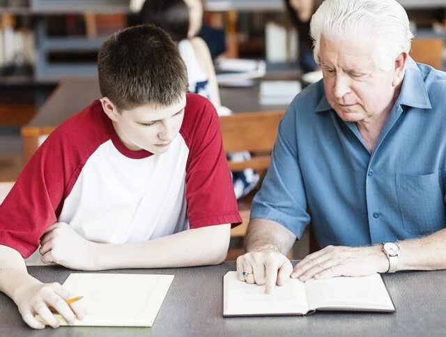 Senior man tutoring a teenager in the library