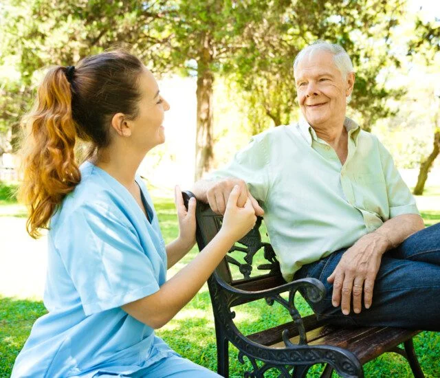 Senior man looking at female nurse holding hands