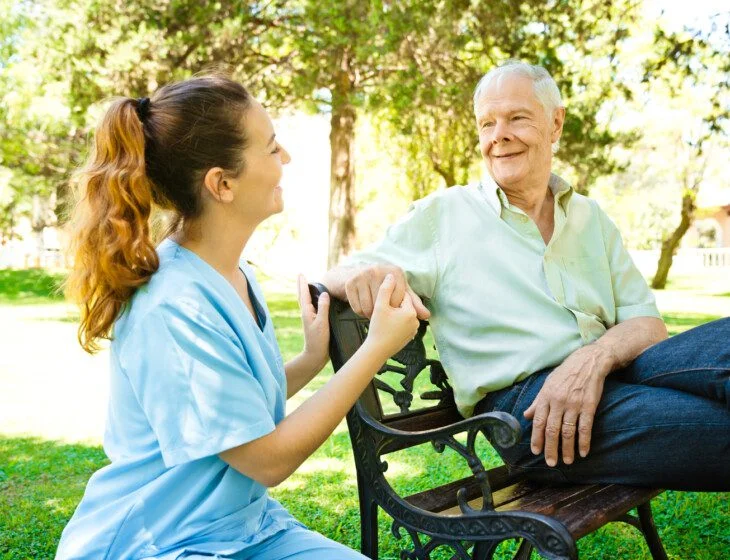 Senior man looking at female nurse holding hands