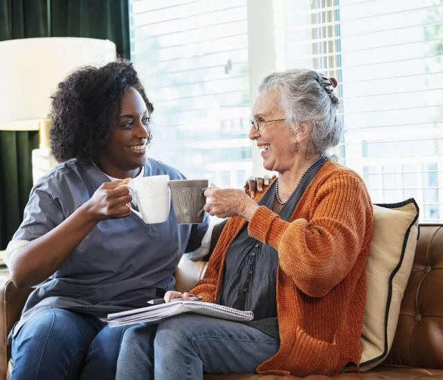 Senior woman having coffee with home caregiver