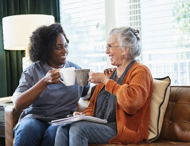 Senior woman having coffee with home caregiver