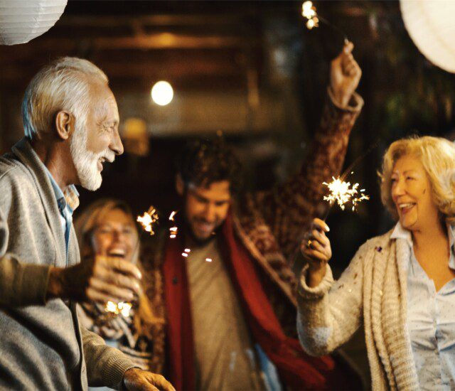 senior couple dances with sparklers under paper lanterns during a celebration