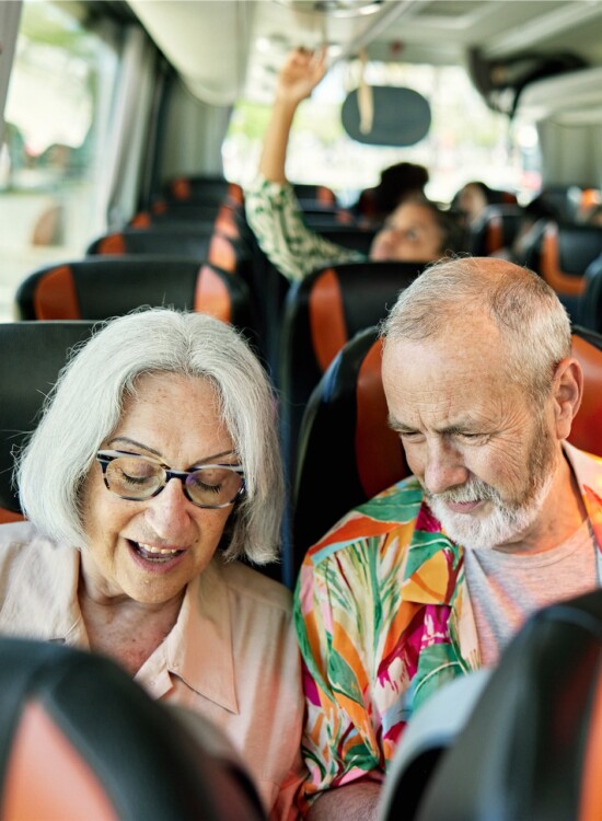 senior couple sits on a bus together heading out for a vacation tour