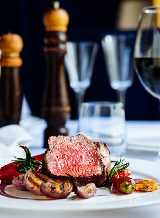 close-up of chef-prepared steak dinner and wine glasses