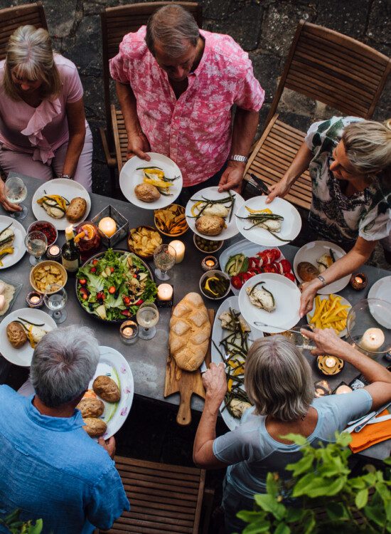 group of seniors smile and share an outdoor meal together