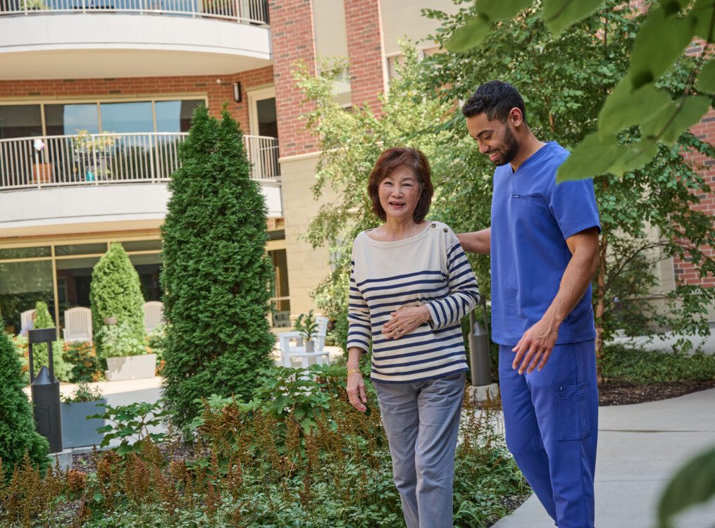 senior woman walks with her caretaker outside