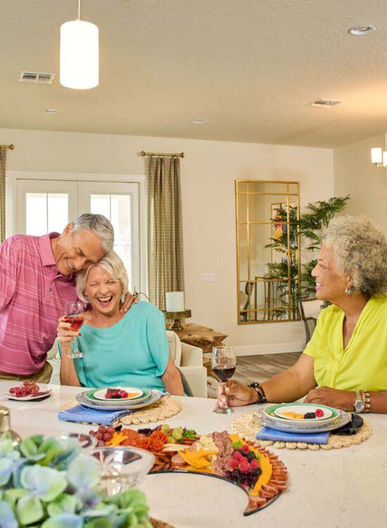 group of seniors gather in a villa home for snacks, drinks, and games