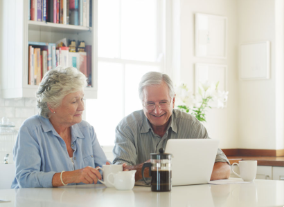 senior couple looking at a laptop together while drinking coffee