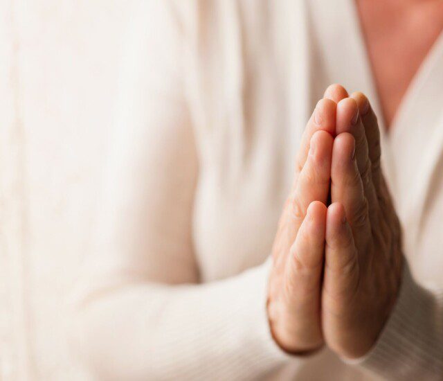 close-up of senior woman's hands placed together for a prayer