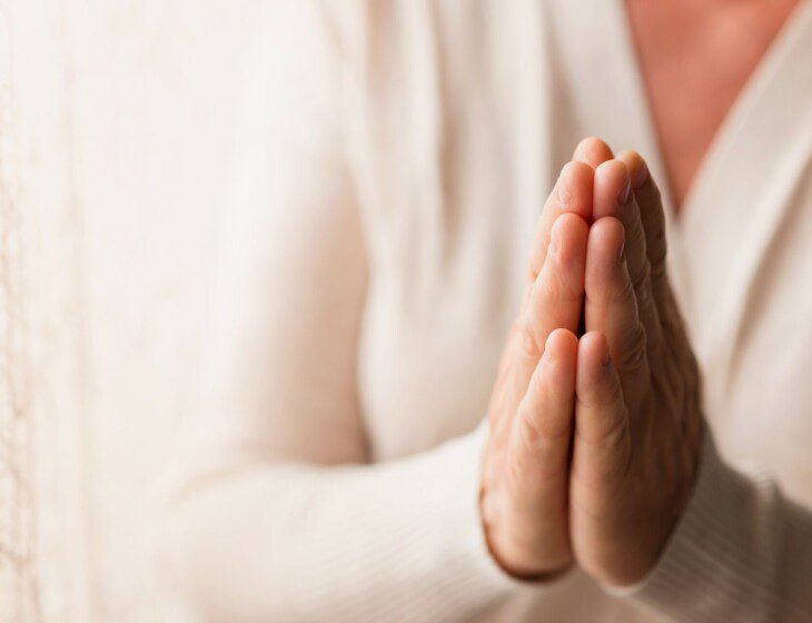 close-up of senior woman's hands placed together for a prayer
