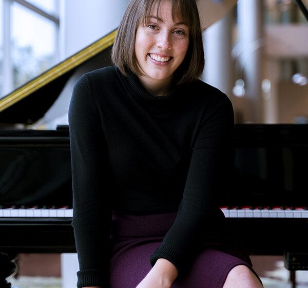 25 year old music student Beth Christensen sits in front of a grand piano at Claridge Court Senior Living Community, smiling