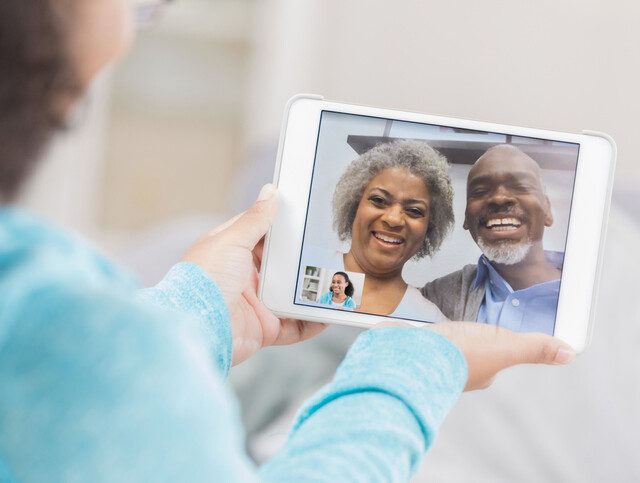 young granddaughter holds tablet, video calling her smiling grandparents