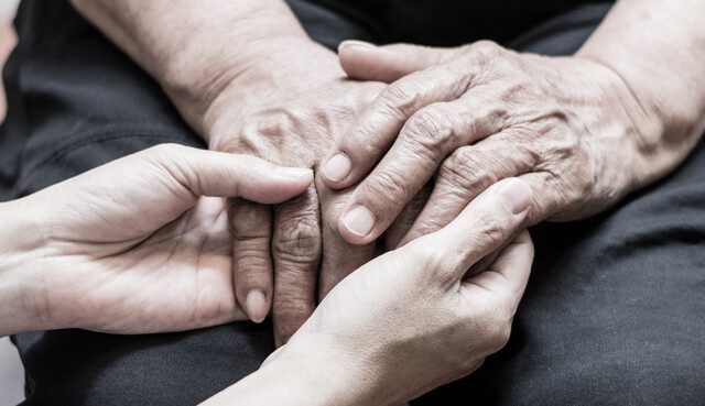 close-up of caregiving holding the hands of senior