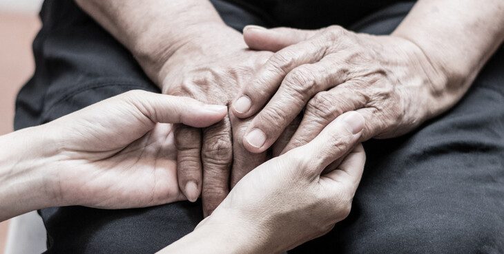 close-up of caregiving holding the hands of senior