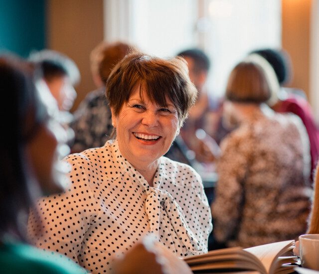 senior women laugh and converse during book club