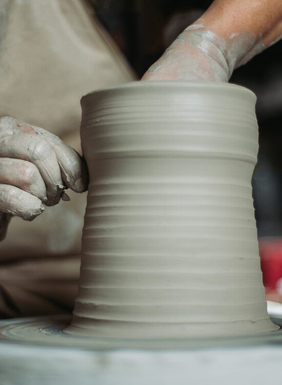 close-up of hands making pottery on wheel