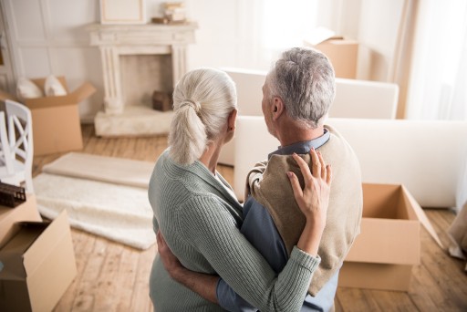 senior couple standing in a living room packing to downsize