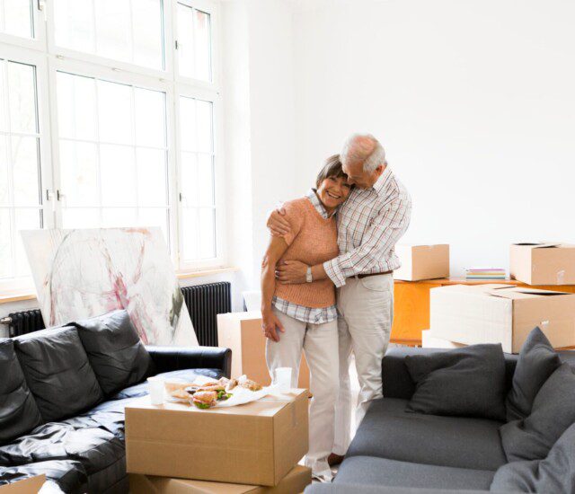 senior couple hugs happily after finishing packing for their move to a senior living community