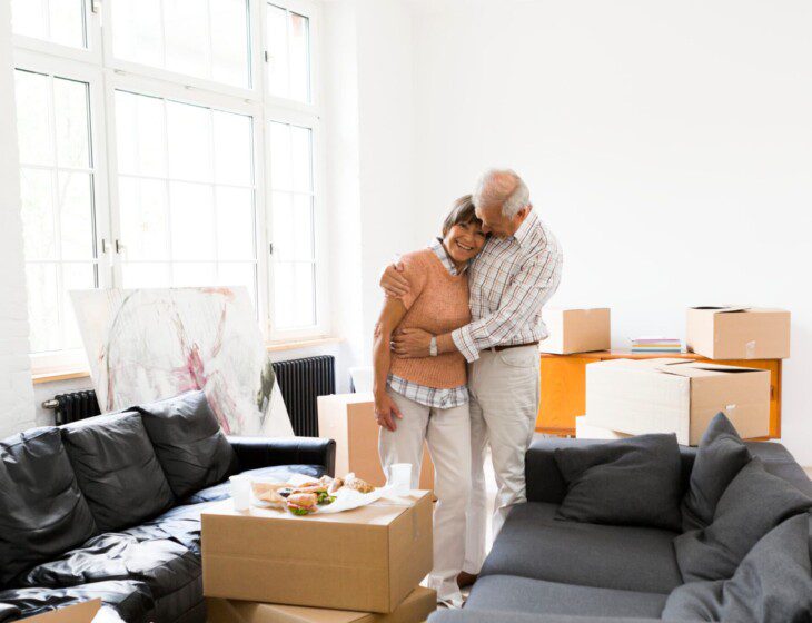 senior couple hugs happily after finishing packing for their move to a senior living community