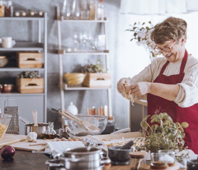 cheerful senior woman in red apron cooks a holiday meal in her contemporary kitchen