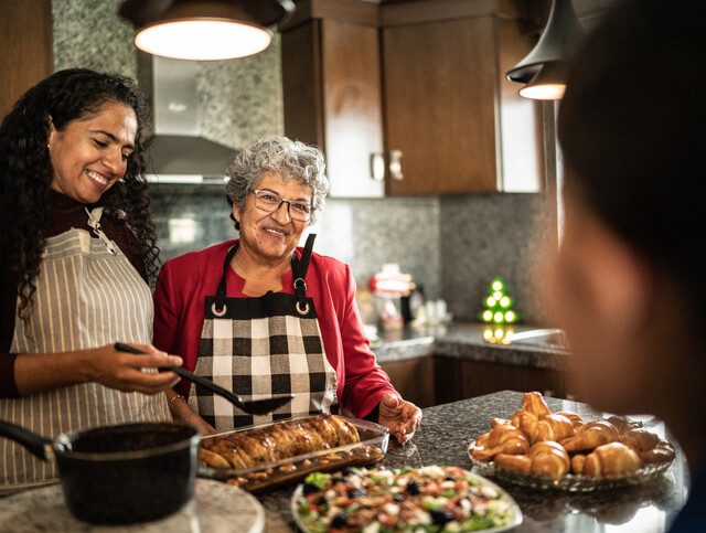 senior woman and her family prepare a holiday meal together in the kitchen, smiling