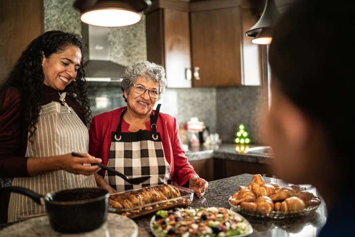 senior woman and her family prepare a holiday meal together in the kitchen, smiling