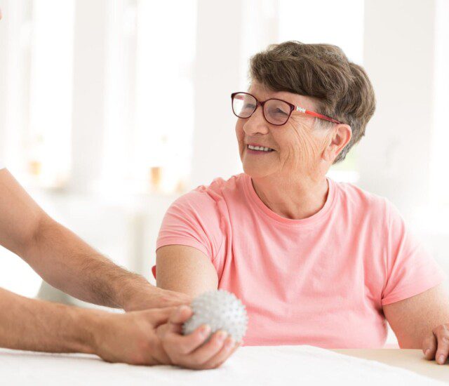 senior woman does physical therapy rehabilitation exercise while seated with the help of a caregiver