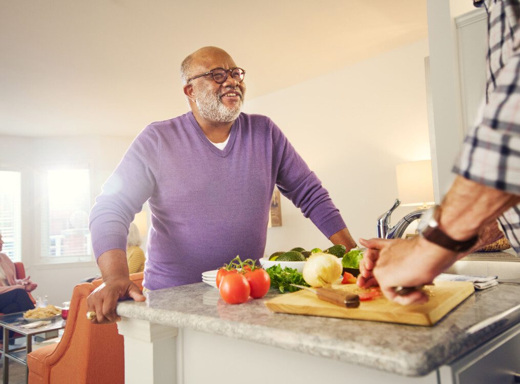 group of seniors prepare dinner together in an apartment townhome