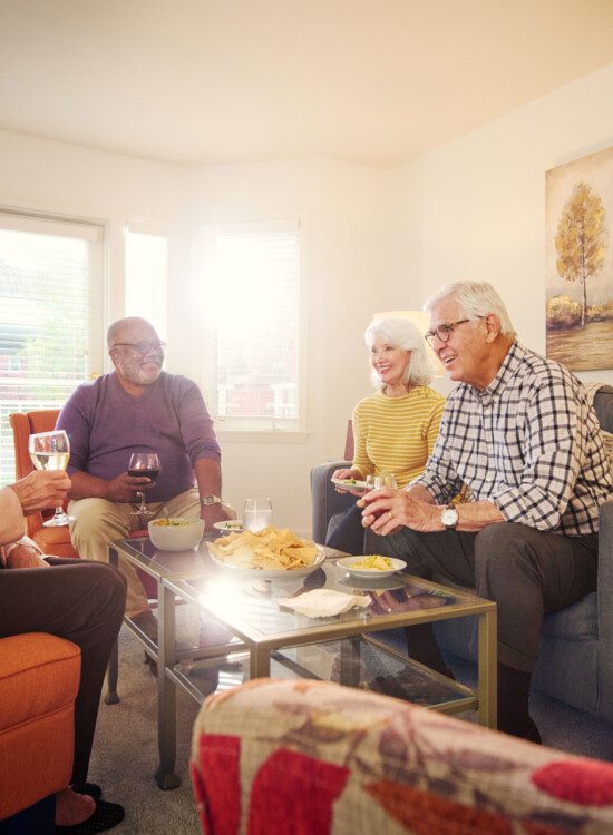 group of senior friends enjoy a meal together in the living room of a apartment townhome