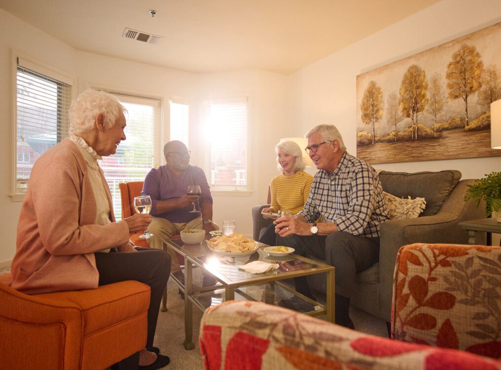 group of senior friends enjoy a meal together in the living room of a apartment townhome