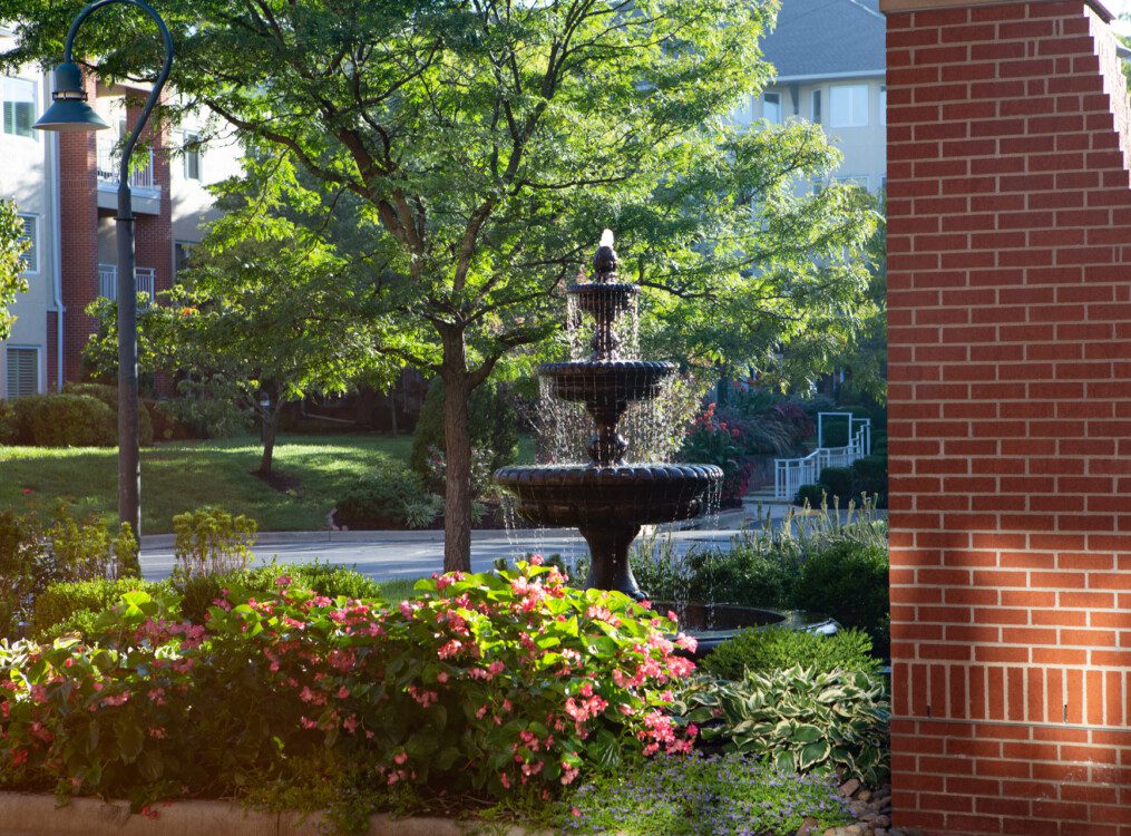 close-up of the fountain and beautiful landscaping in front of the entrance at Claridge Court Senior Living Community