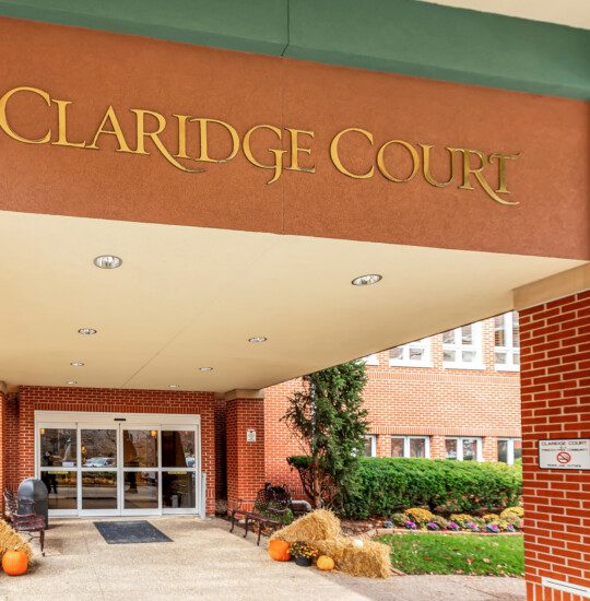 Close-up of entrance at Claridge Court Senior Living Community, featuring golden lettering that denotes the community name on an arch