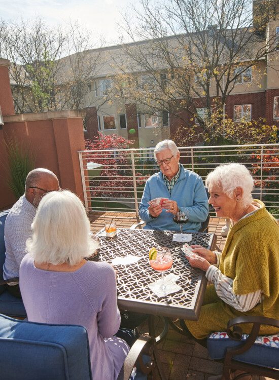 group of seniors play Jenga and enjoy drinks together in a sunny courtyard terrace