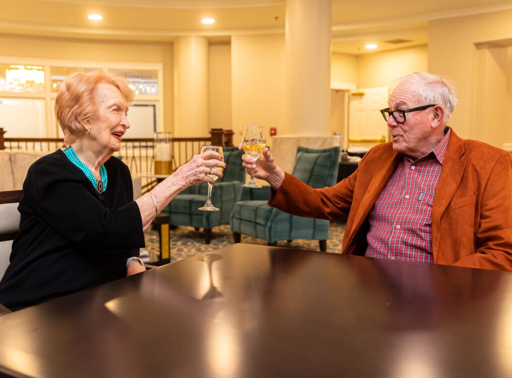 senior couple smile and toast wine glasses at Claridge Court