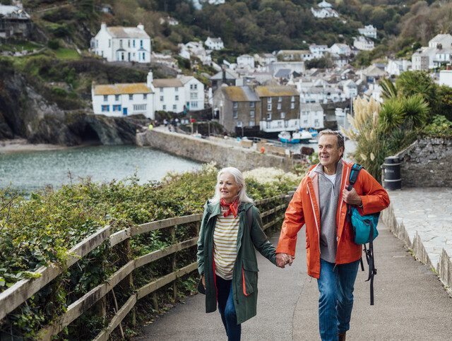 Two seniors walking alongside a lake holding hands